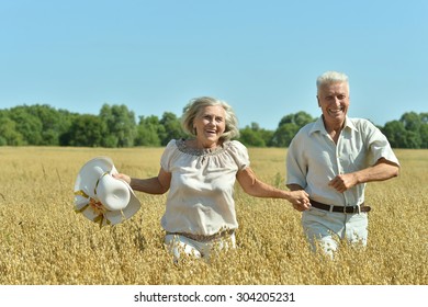 Loving Mature Couple Running  In Field  At Summer