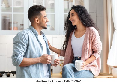 Loving Middle Eastern Couple Bonding While Drinking Coffee In Kitchen, Happy Millennial Arab Man And Woman Holding Cups With Hot Drinks And Enjoying Spending Time Together At Home, Closeup