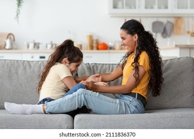 Loving Middle Eastern Mother Playing With Her Cute Little Daughter At Home, Cheerful Young Arab Woman Tickling Happy Laughing Female Child, Having Fun Together In Living Room, Side View, Copy Space