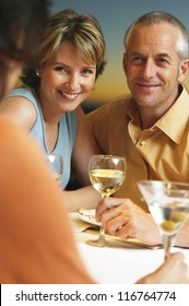 Loving Middle-aged Couple Sitting At The Dinner Table Socialising With Friends