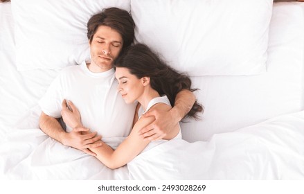 Loving millennial couple sleeping in bed in morning and hugging, love and relationships concept, top view, free space - Powered by Shutterstock