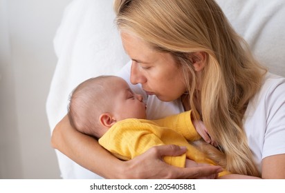 Loving Mom Carying Of Her Newborn Baby At Home. Bright Portrait Of Happy Mum Holding Sleeping Infant Child On Hands. Mother Hugging Her Little 2 Months Old Son