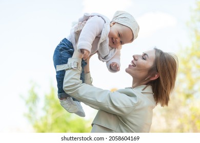 Loving Mom Raises Little Daughter Above Head Outdoors