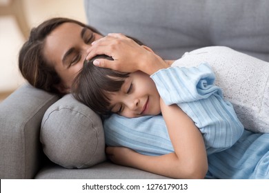 Loving mother caressing cute little daughter lying on sofa together, caring mom embracing kid relaxing enjoying nap, happy mum stroking hugging preschool girl cuddling resting on comfortable couch - Powered by Shutterstock