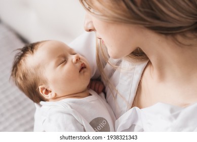 A loving mother carries her newborn baby at home. portrait of a happy mother holding a sleeping baby in her arms. Mother hugs her little 4-month-old daughter