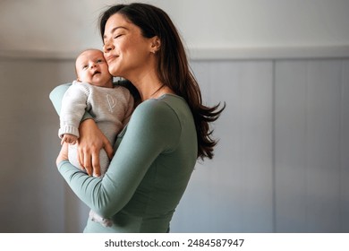 Loving mother carrying of her newborn baby at home. Family parenting baby single mother love concept