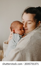 Loving Mother Carying Of Her Newborn Baby At Home. Bright Portrait Of Happy Mum Holding Cute Infant Child On Hands. Mother Hugging Her Little 1 Months Old Daughter.