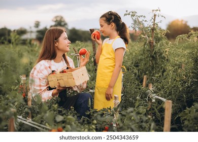 A loving mother and daughter enjoy picking ripe tomatoes together in a vibrant garden, symbolizing family bonding and sustainable living. - Powered by Shutterstock