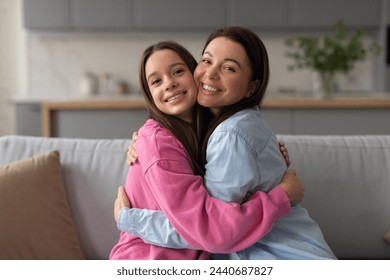 Loving mother hugging embracing her happy teen daughter at home, expressing love to teenage child, sitting together on couch and cuddling - Powered by Shutterstock