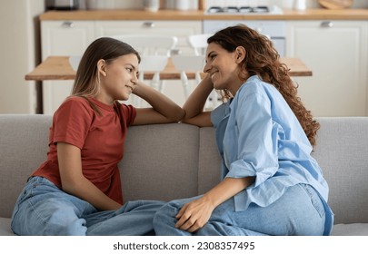 Loving mother listening to daughter with empathy and understanding while sitting together on sofa bonding at home, pre-teen girl child sharing secrets with mom, parent communicating with teenager - Powered by Shutterstock