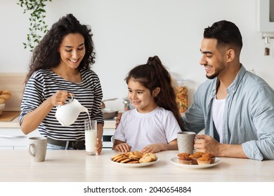 Loving mother middle-eastern young woman pouring fresh milk for her cute little daughter, happy arabic family having breakfast together at home, kitchen interior. Healthy food, diet cocnept - Powered by Shutterstock