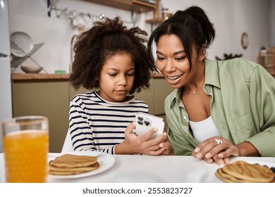 A loving mother shares a moment with her little daughter while enjoying breakfast together. - Powered by Shutterstock