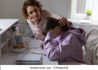 Loving mother supporting tired teenage daughter study together at home. Worried young parent mom helping comforting sad teen encouraging school girl having difficulty with education learning at home.