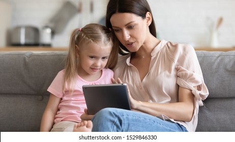 Loving Mother Teaching Little Daughter To Use Computer Tablet Close Up, Shopping Or Playing Online, Sitting On Couch Together, Young Mum And Preschool Child Looking At Electronic Device Screen