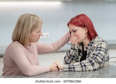 Loving Mother And Teen Daughter Sit At Home, Worried Parent Calms Crying Girl. Teenagers Problem Concept.