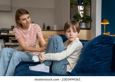 Loving mother trying to speak with upset depressed teen son while sitting together on sofa at home, mom comforting teenage boy child, showing support. Anger in adolescents. Kid problem concept.  - Shutterstock ID 2303494361