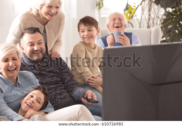 Loving multigenerational family laughing while\
watching television\
together