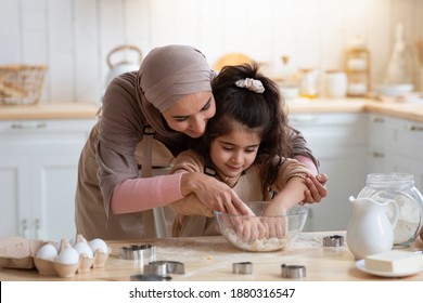 Loving Muslim Mom Teaching Daughter How To Knead Dough, Having Fun Together In Kitchen At Home, Woman In Hijab Helping To Her Little Child, Islamic Family Enjoying Making Homemade Pastry, Free Space