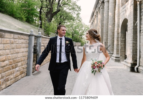 Loving newlyweds hold hands and run, looking each\
other in the eyes