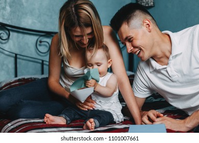 Loving parents sitting on bed at home laughing playing developing game with their little baby daughter. Childhood, parenthood, child development, togetherness, love, happiness concept - Shutterstock ID 1101007661
