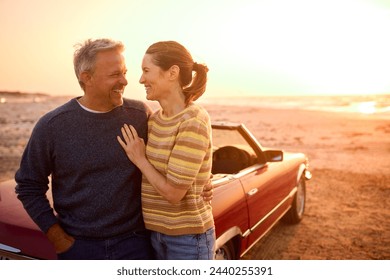 Loving Retired Senior Couple On Vacation Next To Classic Sports Car At Beach Watching Sunrise - Powered by Shutterstock