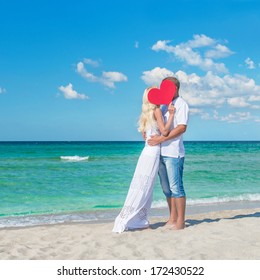 Loving Romantic Hug Couple At Sunny Sea Beach With Red Heart Symbol - St.Valentines Day Concept