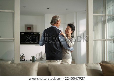 loving romantic senior asian couple dancing in living room at home