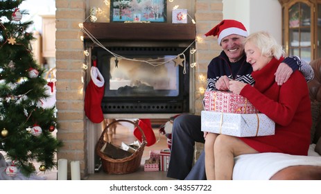 Loving senior couple exchanging gifts on christmas morning or new year day in decorated living room with fireplace and xmas tree. - Powered by Shutterstock