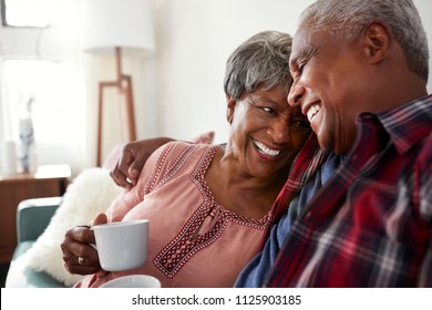 Loving Senior Couple Sitting On Sofa At Home Relaxing With Hot Drink - Powered by Shutterstock