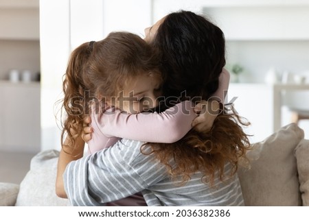 Loving small child girl cuddling affectionate mother after long separation time, showing tender sweet feelings at home. Happy two female generations family embracing, warm relations concept.
