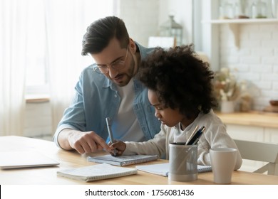 Loving Stepdad Or Tutor Helps Understand Arithmetic Task Provide Care And Patience During Homeschooling With Little Mixed-race African Daughter Kid Girl. Child Development, Schoolwork At Home Concept