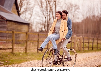 Loving Transgender Couple With Woman Riding On Handlebars Of Bike In Autumn Or Winter Countryside - Powered by Shutterstock