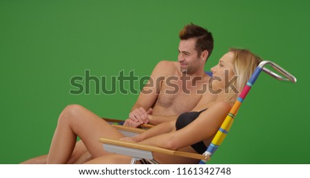 Loving white couple in swimsuits relaxing on beach chairs on green screen