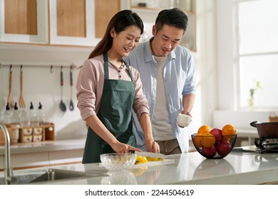 loving young asian couple chatting talking conversing in kitchen at home while preparing food - Powered by Shutterstock