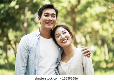 Loving Young Asian Couple Relaxing Outdoors In Park