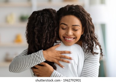 Loving Young Black Woman Mother Hugging Her Daughter With Closed Eyes And Smiling, Home Interior, Closeup. Happy African American Mom Embracing Her Female Kid, Feeling Precious