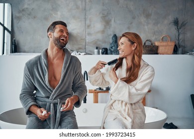 Loving young couple in bathrobes laughing while doing morning routine - Powered by Shutterstock