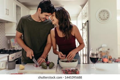 Loving Young Couple Cutting Vegetables Together At Kitchen Counter. Young Man And Woman In Love Cooking Food Together At Home.