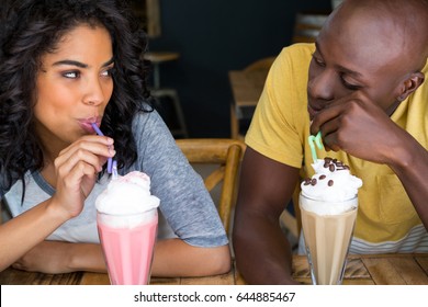 Loving Young Couple Having Milkshakes At Table In Coffee Shop