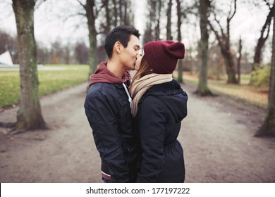 Loving Young Couple Kissing Outdoors In The Park. Mixed Race Man And Woman. Teenage Love.