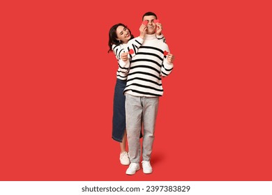 Loving young couple with paper hearts on red background. Celebration of Saint Valentine's Day
