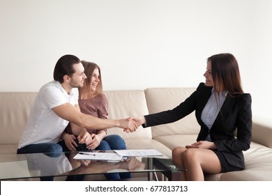 Loving young couple shaking hands with friendly real estate agent, satisfied clients and female manager handshaking, bank loan approved, personal insurance, lease agreement, mortgage investment