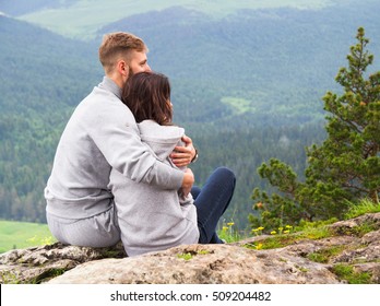 Loving young couple sitting on a mountain, hugging and looking away, love and feelings concept. - Powered by Shutterstock