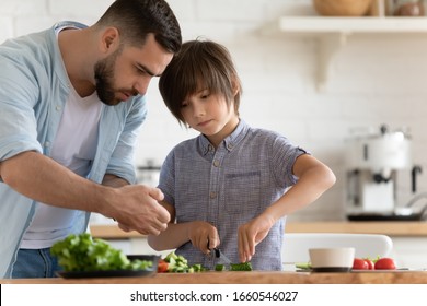 Loving young father and little preschooler son cooking together chopping vegetables for salad in modern kitchen, caring dad teach small boy child preparing lunch or dinner at home, dieting concept - Powered by Shutterstock