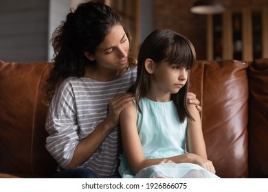 Loving Young Latino Mother Hug Caress Small 8s Daughter Feeling Offended Or Upset. Caring Hispanic Mom Embrace Support Or Comfort Sad Little Girl Child, Reconcile Make Peace. Generation Gap Concept.