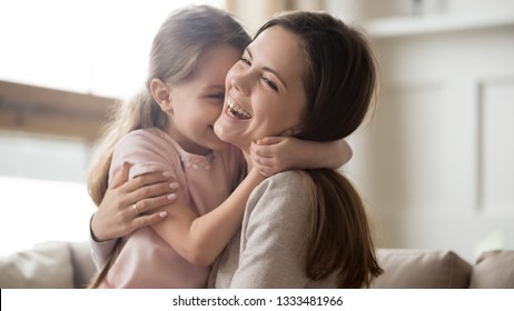 Loving young mother laughing embracing smiling cute funny kid daughter enjoying time together at home, happy family single mom with little child girl having fun playing feel joy cuddling and hugging