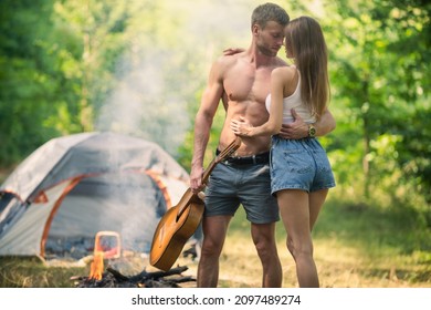Loving young sexy coupl near camp tent. Camping couple in love. Couples of lovers tourists relax on nature. Camping trip with lovers. Carefree coupl near campfire bonfire, freedom concept.