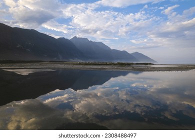 A low aerial shot of mountains and sky reflecting off still water in Eastern Taiwan