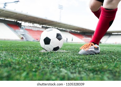 Low angle action shot of unrecognizable teenage boy forcefully kicking ball during football match on outdoor stadium, copy space