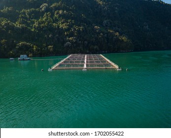 Low Angle Aerial Image Of A Fish Farming Operation In Chile On A Sunny Day.